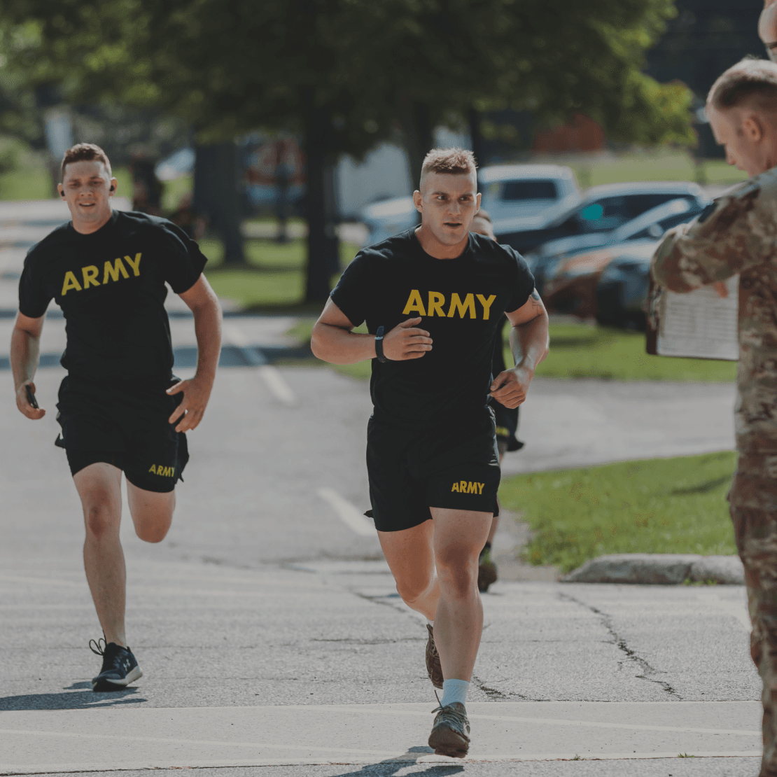 Two soldiers sprinting toward a grader at the finish line